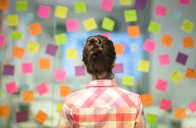 A woman stares at dozens of post-it notes. Some people experience bursts of creativity and productivity during episodes of hypomania.