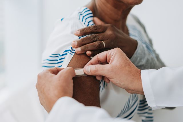 doctor applying a bandaid on a patient's arm after flu shot