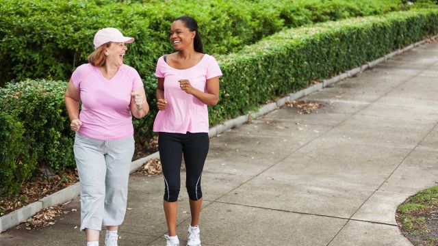 Two women walking, laughing, and wearing pink for breast cancer awareness