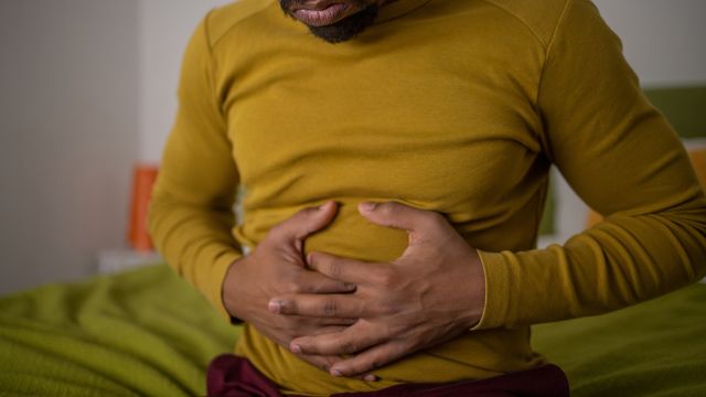 A man holding his stomach to help with the harsh effects of inflammatory bowel disease.