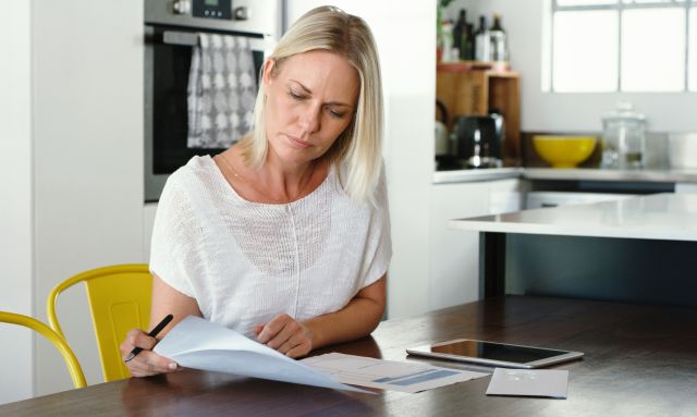 a blonde middle aged white woman reviews health insurance documents to try to understand the details of her coverage