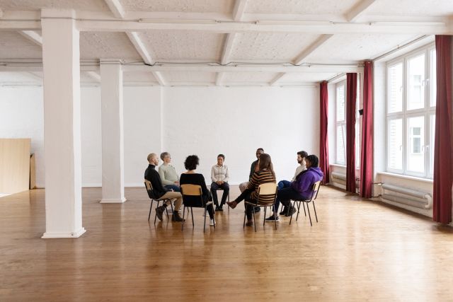 A support group for caregivers meets in a spacious room. Support groups can help caregivers connect with other people who have similar experiences.