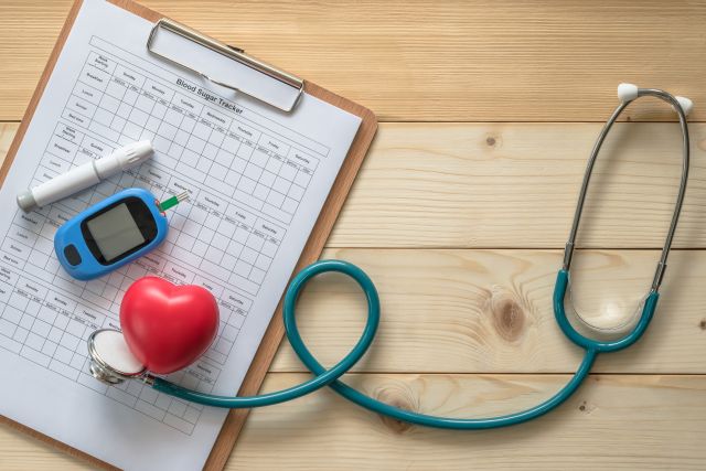 red heart, stethoscope, blood sugar finger stick, blood sugar tracking sheet