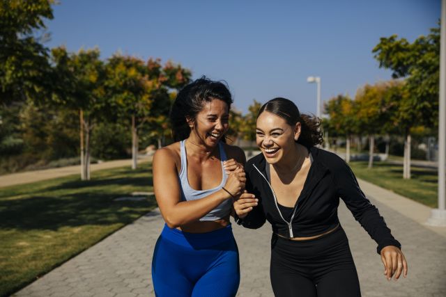 two friends laughing and exercising together outside
