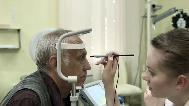 A senior-aged man has his eye examined by an oncologist. Uveal melanomas begin in the uvea, the middle layer of the eyeball.