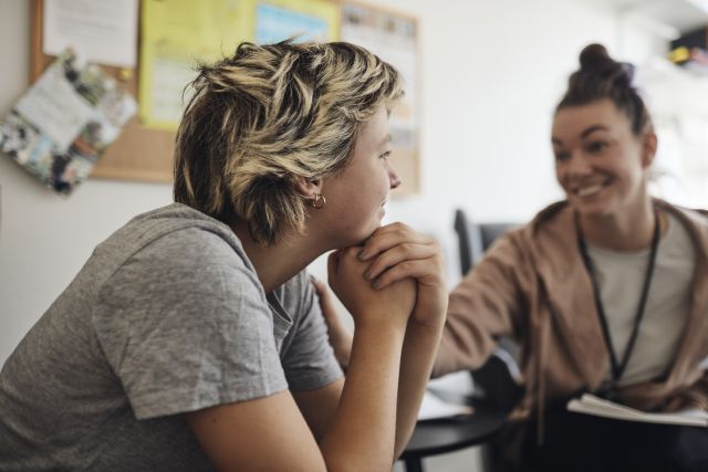 a young transfeminine patient sits and speaks with a therapist in an office