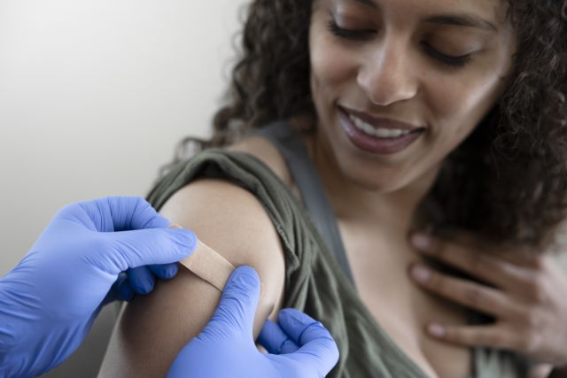 Black adult female getting bandaid on her arm after receiving a flu shot