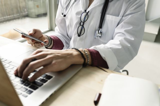 doctor getting information on smartphone and laptop computer