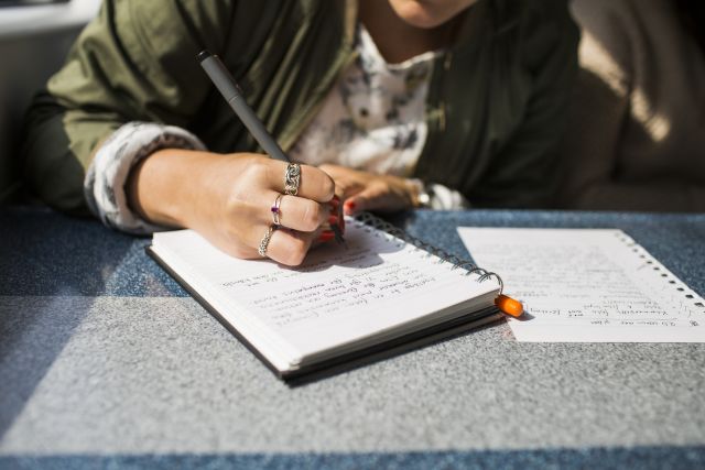 A woman writes in a journal to record her psoriasis symptoms over the past week.