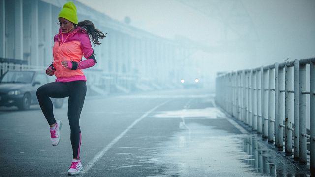 A woman goes for a run on a cold, rainy day.