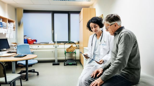 A middle-aged man speaks with a neuro-oncologist in an exam room.