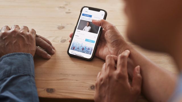 A senior man and their adult child caregiver watch a video on Parkinson's disease on a phone.