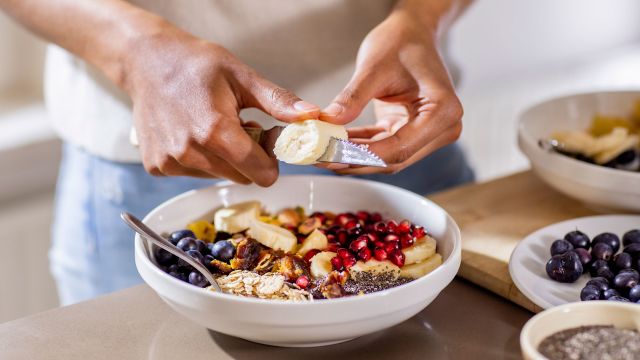 Man cutting up bananas and fruit to go in fiber-rich oatmeal