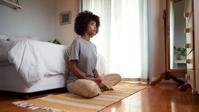 Woman meditating at the foot of her bed to manage stress