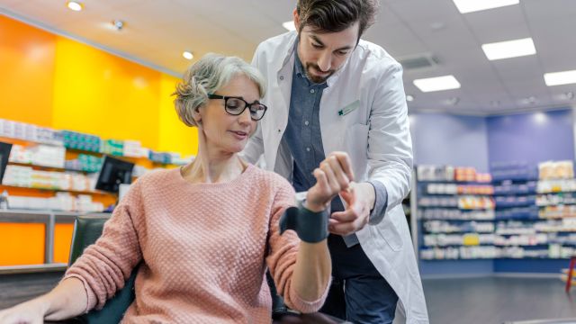 A senior woman has her blood pressure checked by her pharmacist.