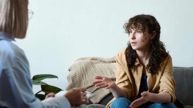 A young woman speaks to a therapist during an appointment for cognitive behavioral therapy.