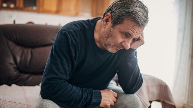 A senior man sits alone in his living room. Depression is a risk factor associated with Parkinson's disease psychosis.