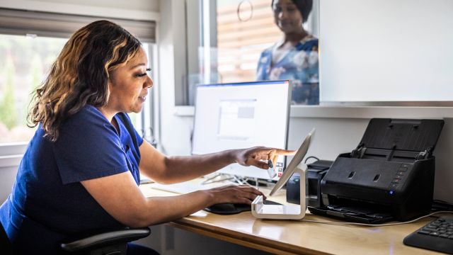 A female nurse accepts payment from a caregiver who has accompanied a loved one to an appointment for an anti-VEGF injection to treat wet AMD.