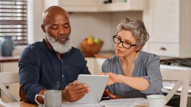 A senior man helps his partner prepare for a healthcare appointment to discuss symptoms of Parkinson's disease psychosis.