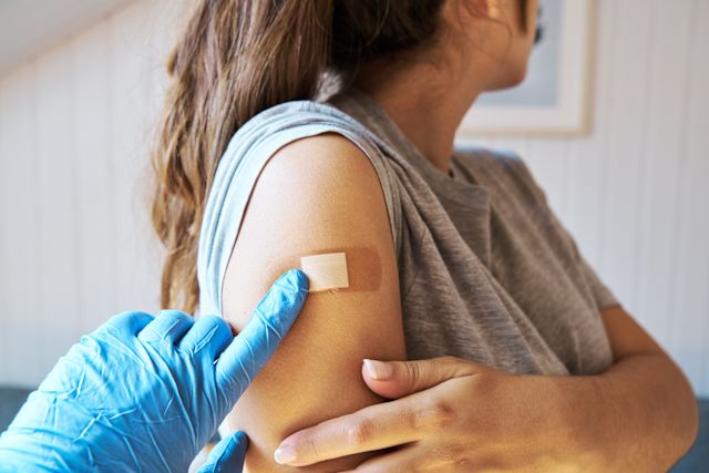 adult woman with bandaid on her arm following vaccination