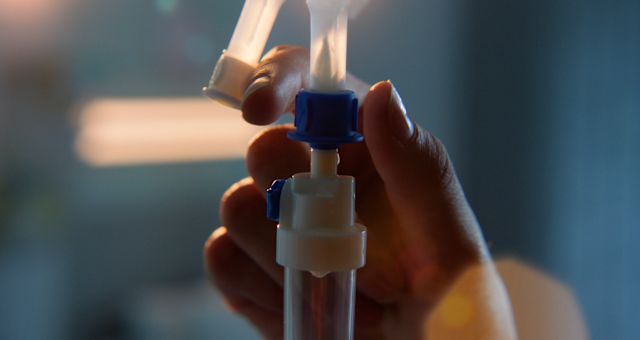 A closeup of a healthcare provider's hands as they check that an intravenous infusion is working. Intravenous immunoglobulin is the most commonly used treatment for CIDP.