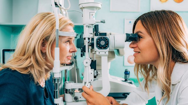 A senior woman has her eyes examined by an ophthalmologist. Follow-up appointments for monitoring and treatment are an essential part of managing an advanced form of age-related macular degeneration.