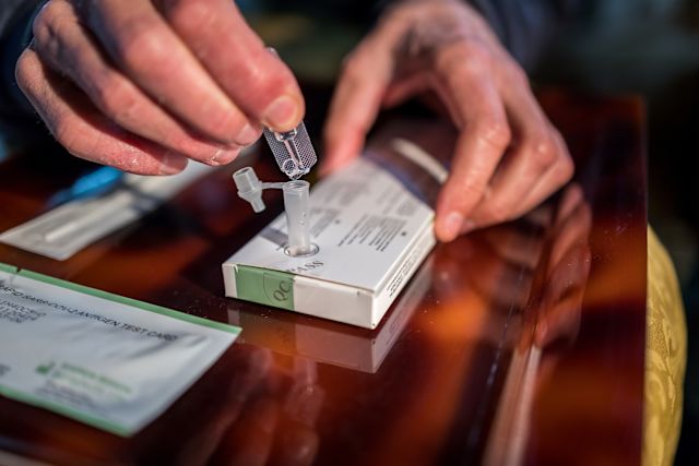close up of adult hands performing rapid home COVID test with a testing kit