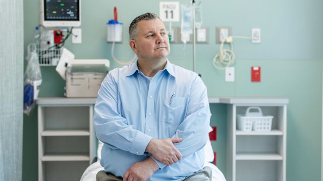 An overweight man sits in an exam room waiting to see his healthcare provider.