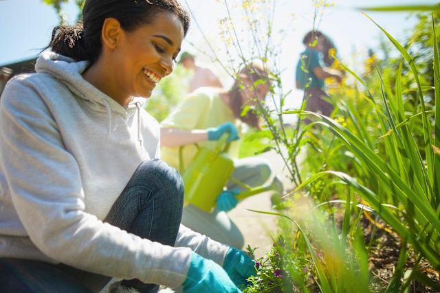 adult Latino woman smiling as she volunteers in a community garden