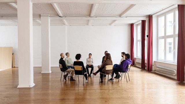 A support group for caregivers meets in a spacious room. Support groups can help caregivers connect with other people who have similar experiences.