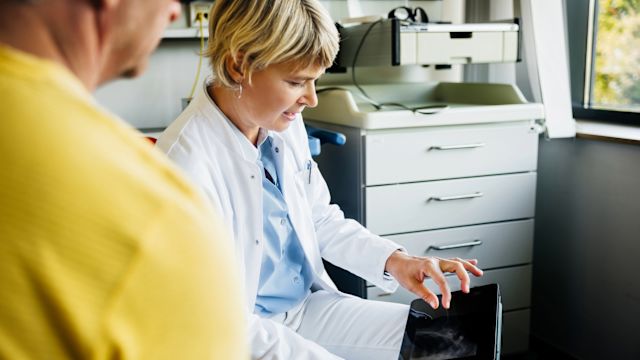 A healthcare provider uses a tablet as she explains the procedure of subcutaneous immunotherapy to a male patient in his 60s.