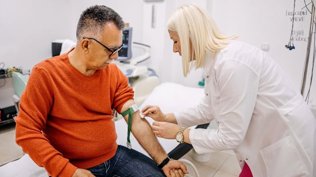 A healthcare provider draws blood from the arm of a male patient in his 60s during an appointment. Blood work, including complete blood counts, are an important tool in diagnosing MDS.