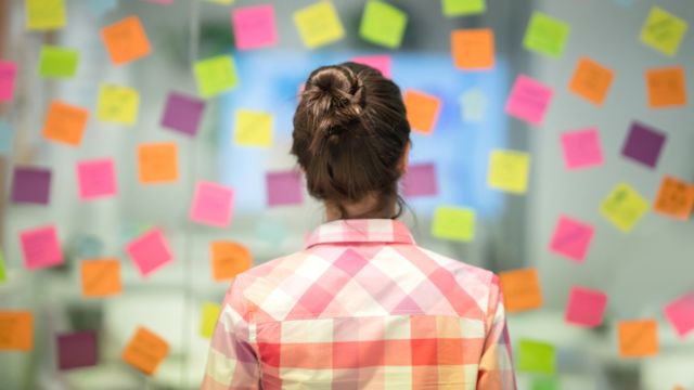 woman looking at wall of post-it notes
