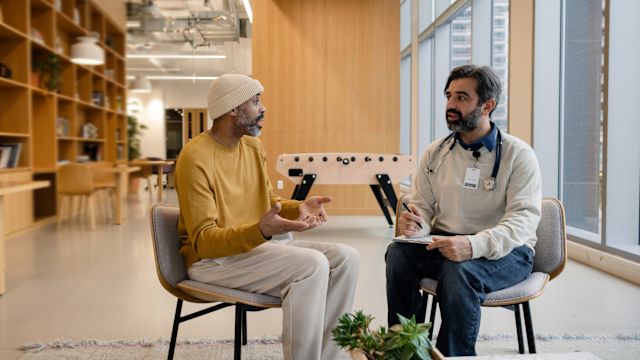 An adult man with CIDP speaks with a new healthcare provider in a common area of a hospital.