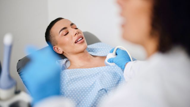 A healthcare provider performs an ultrasound on the breast of a female patient as part of a diagnosis of triple negative breast cancer.