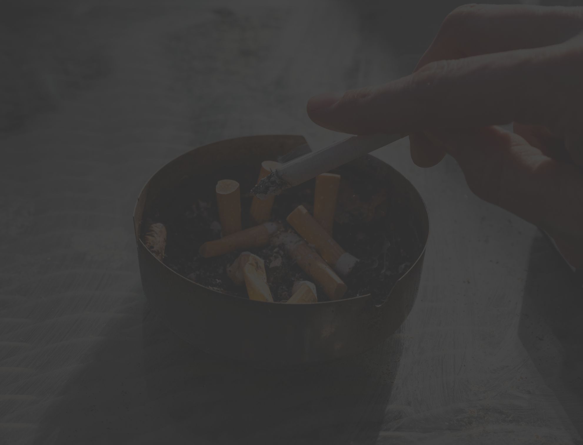 closeup of a hand ashing a cigarette in a tray