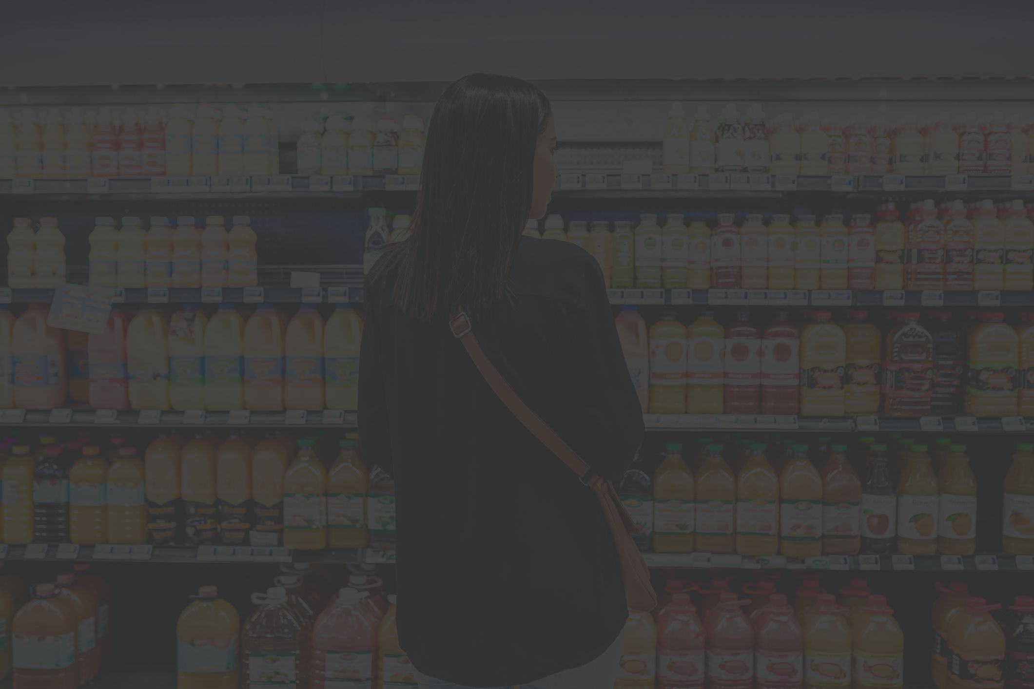 woman looking at juice on shelves at market