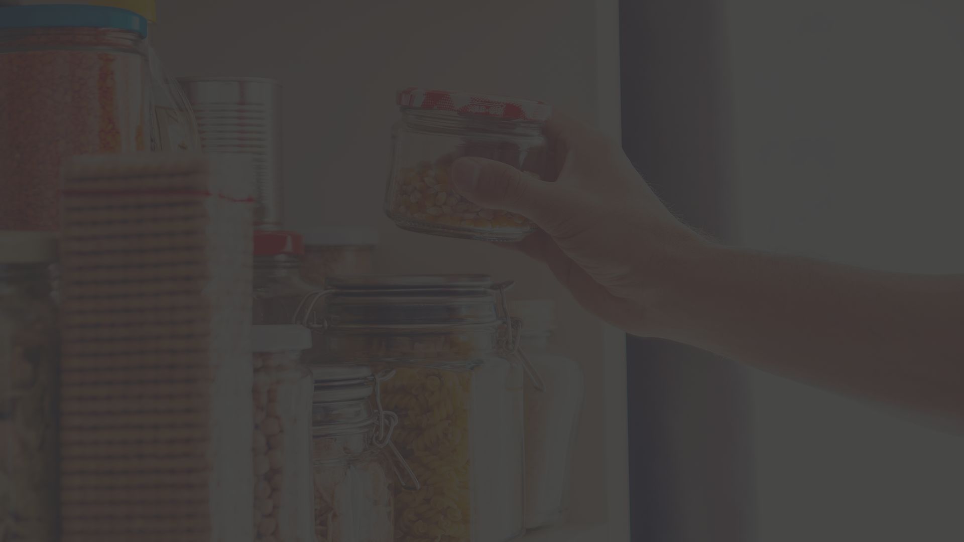 hand reaching into a pantry to pull out pasta in a glass jar