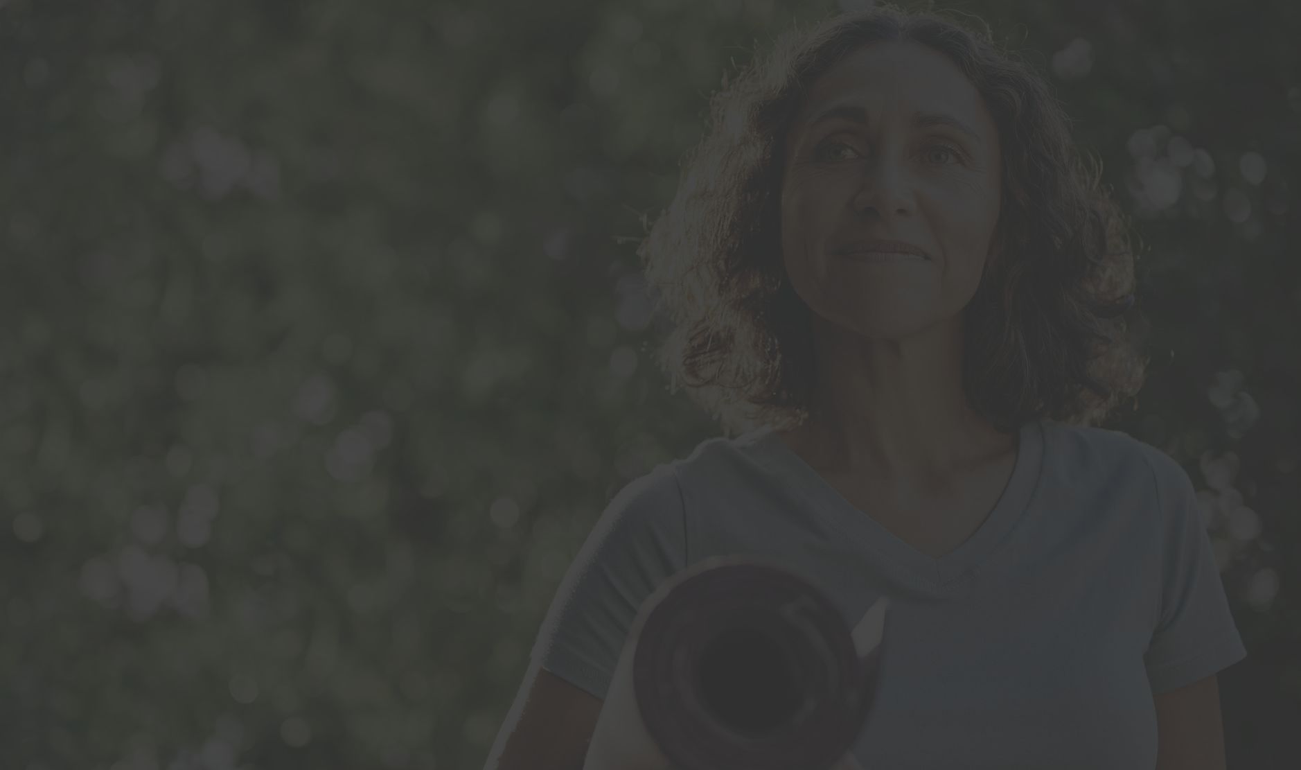 mature woman carrying yoga mat outdoors